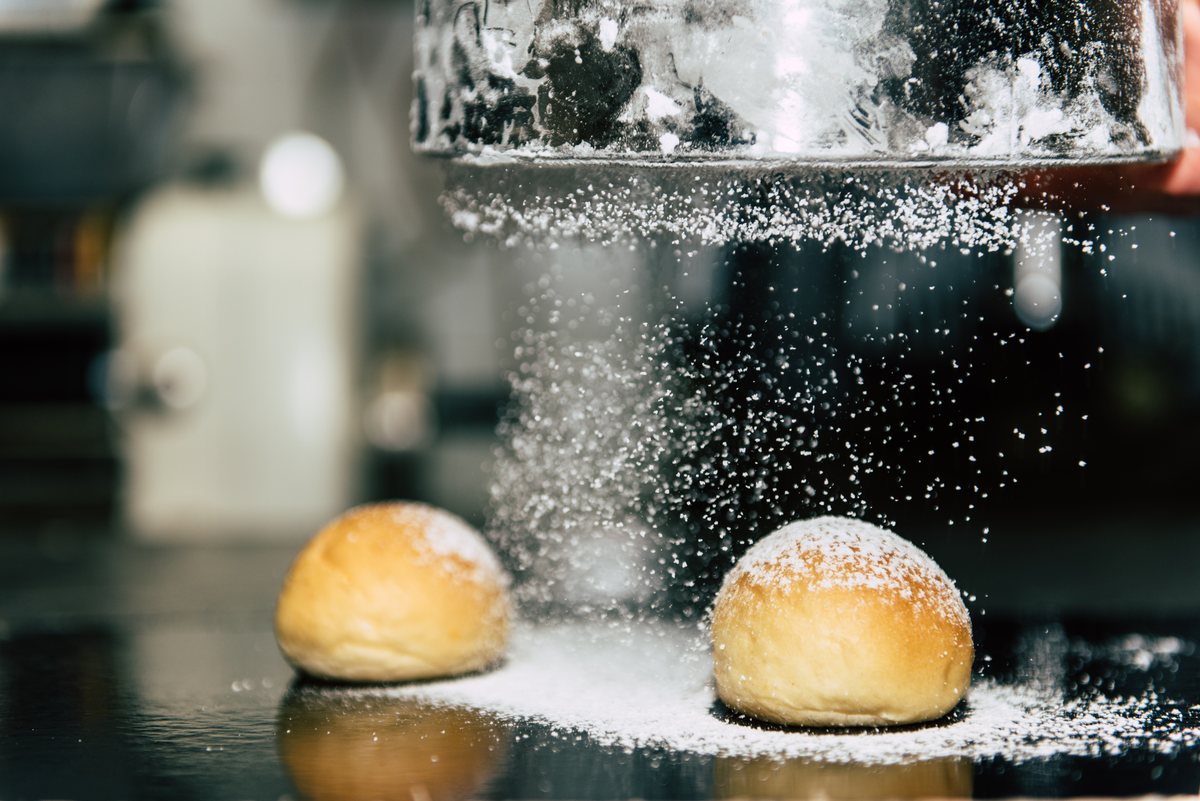 Zucchero a velo spolverato sui bomboloni appena fritti della pasticceria a Lamezia Terme