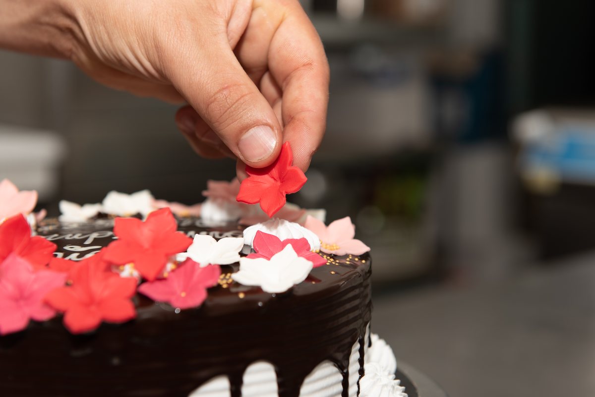 Decorazione a mano con fiori di zucchero su una torta al cioccolato a Lamezia Terme